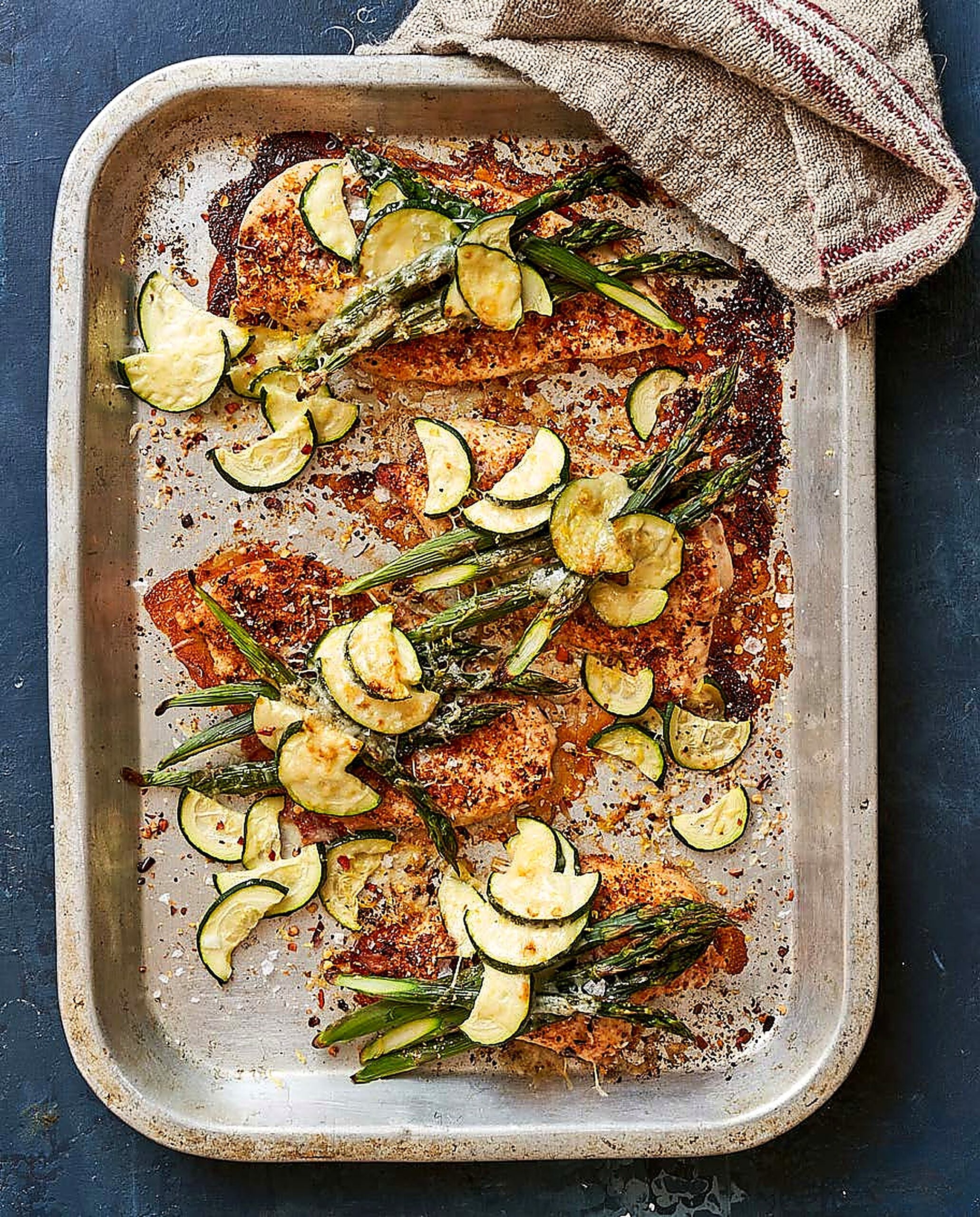 Peri peri chicken cheddar bake in a roasting tray with asparagus and courgette, golden spiced crust, overhead shot